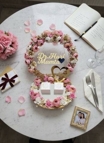Decorative floral arrangement with 'Dr Hari Mama' on a marble table with flowers and a book.