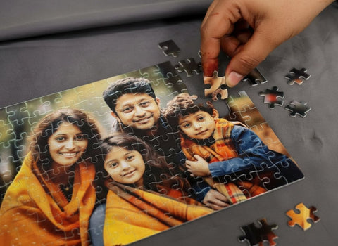 Hand completing a puzzle of a family photo on a gray surface