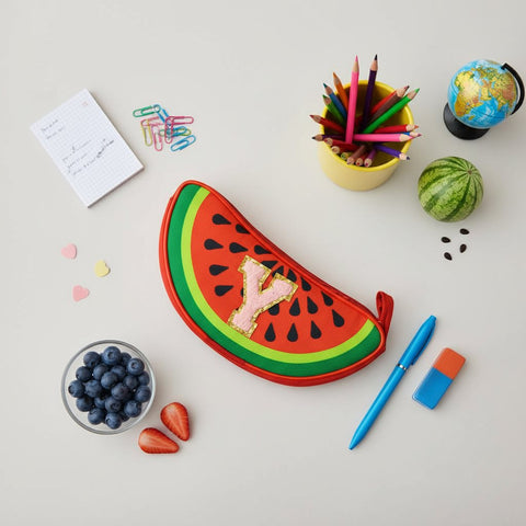 Watermelon-shaped pencil case on a desk with stationery items