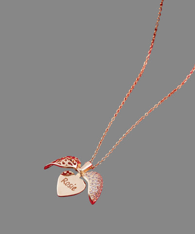 Gold necklace with heart-shaped pendant and 'Rosie' engraving on a red fabric background