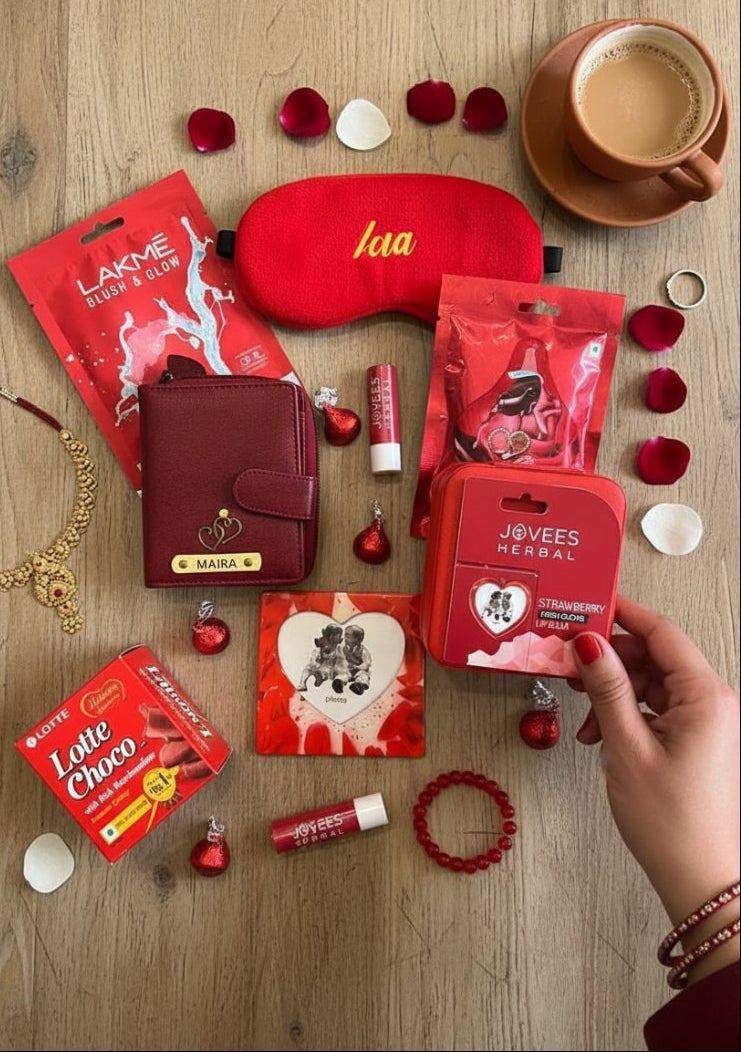 Collection of beauty products including a sleep mask, lip balm, and pouches on a wooden surface with red rose petals.