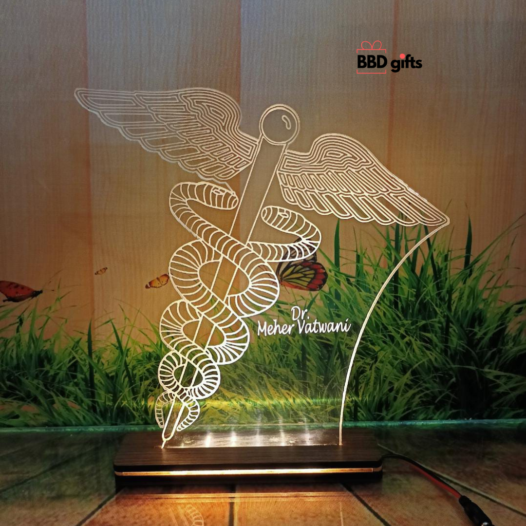 specially made for doctors, it is a table top with led, big doctor symbol is engraved,we can engrave any custom logo and we can engrave custom name. placed on floor adapter wire connection is visible light is on background grass is visible.