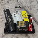 A gift set including a black thermos labeled custom name a pen with a medical symbol, a keychain with a stethoscope charm, a perpetual calendar with custom name inscribed, and a miniature doctor’s coat. The set is presented on a black tray with a pink fabric background.