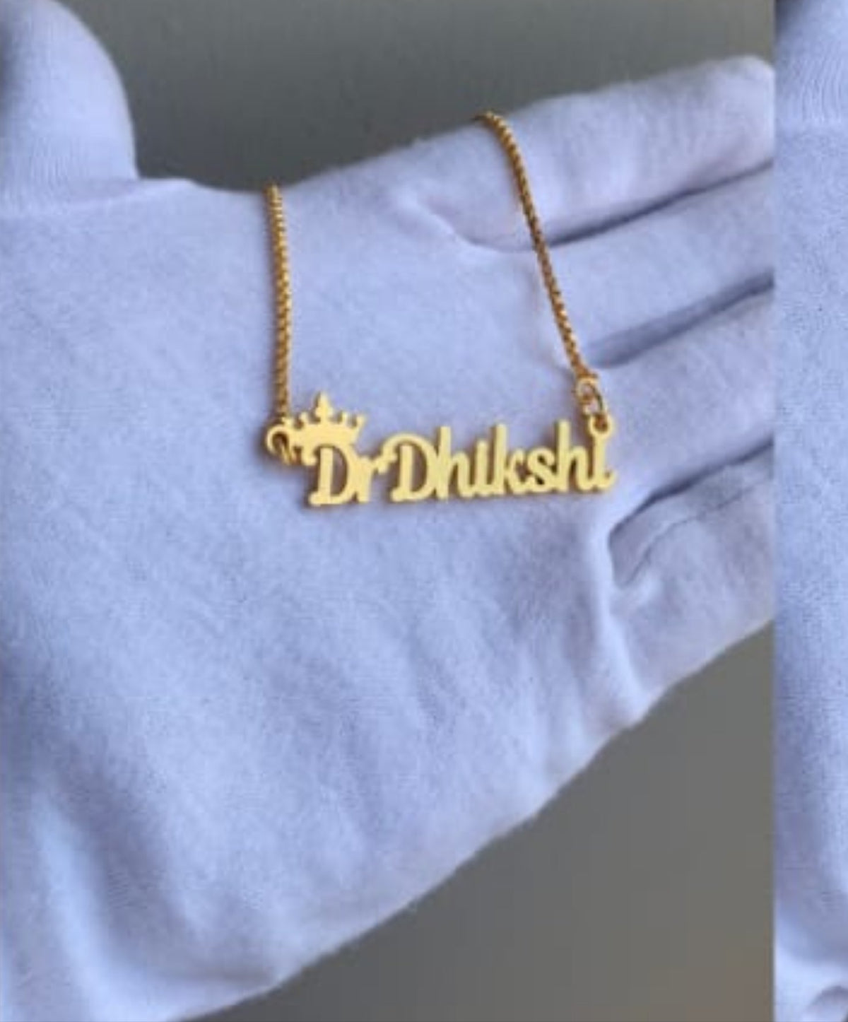 gloves waring hand holding a customized name pendant in gold color chain. fully personalized name pendent with name