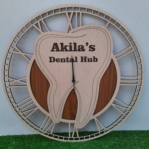 A stylish wall clock designed for a dental office, featuring a large wooden tooth at the center. The clock has an elegant Roman numeral frame and the CUSTOM text displayed prominently on the tooth. The clock is placed on green floor front of white wal