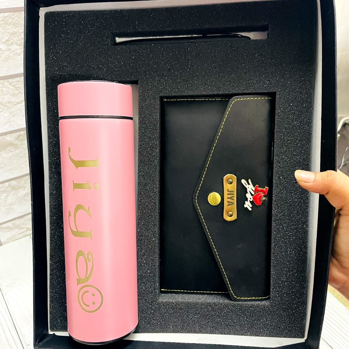 pink color customized water bottle, clucth with custom name and charm, there one balck color pen placed all together in box.