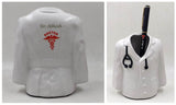 white ceramic apeon coat penstand with stethoscope on hanging neck and 1 balck pen is place inside of the penstand ,another pic shows back side of the pic where red colored doctor symbol is printer with custom name.